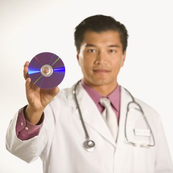 Asian American male doctor holding out compact disc.