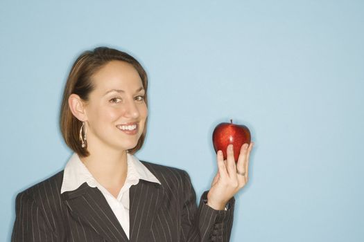 Caucasian businesswoman smiling holding red apple.