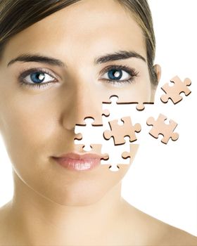 Face of a beautiful young woman with a puzzle collage.