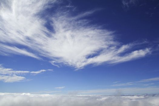 Photo of the clouds taken from a mountain top, with more clouds above it.