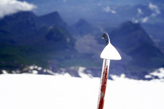 An climbing axe on top of a volcano, covered in snow, with the lower mountains in the background, in Chile