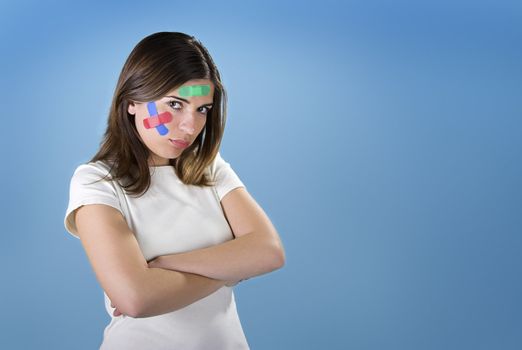 Beautiful woman with colored bandages on the face over a blue background