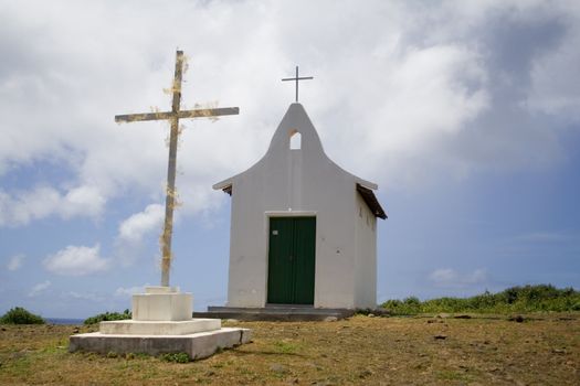 A small white chapel with green doors and a cross.