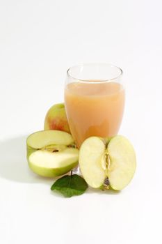 A glass of apple juice with fresh apples on bright background
