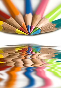 A macro shot of seven bright coloured pencils. 

(with water reflection)