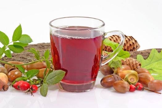 Fruit tea with rosehips and autumnal decoration on bright background
