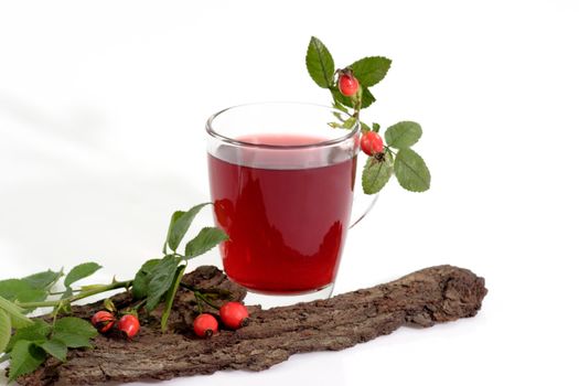 Fresh rosehip tea in a glass with autumnal decoration on bright background