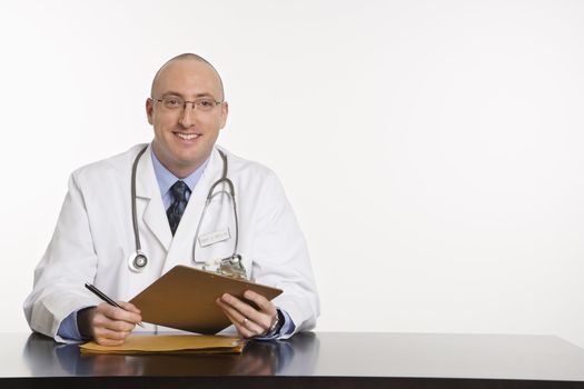 Caucasian mid adult male physician sitting at desk smiling.