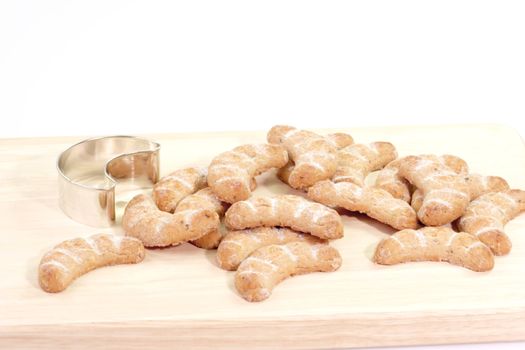 Vanilla cookies and cookie cutter on a wooden kitchen board