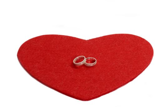 Red heart with two silverrings on white background