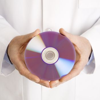 Close up of Caucasian mid adult male physician holding compact disc.