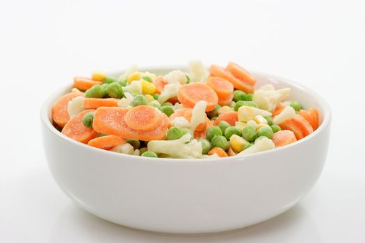 Frozen vegetables in a bowl on light background