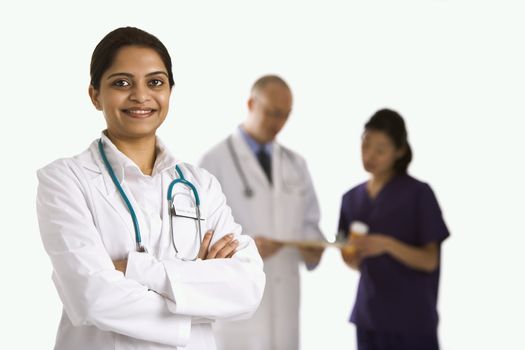 Indian mid adult woman doctor standing with medical staff in background.