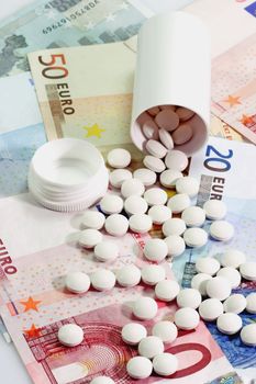 Open pill container with tablets on Euro notes