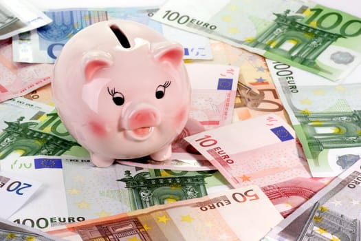 Pink piggy bank on euro notes