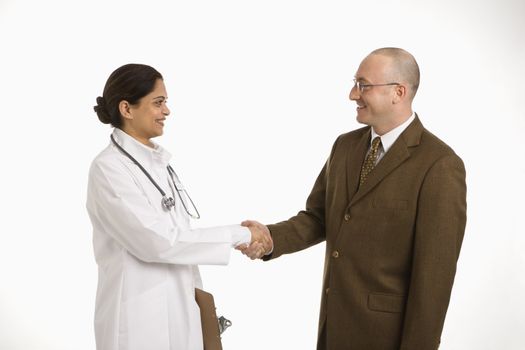 Indian mid adult woman doctor shaking hands with man in business suit.
