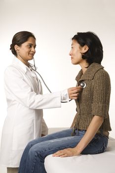 Indian woman doctor using stethescope on Asian woman patient.