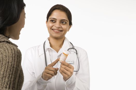 Indian woman doctor explaining medication to Asian woman patient.