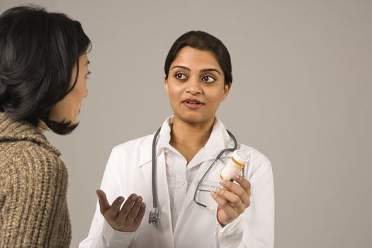 Indian woman doctor explaining medication to Asian woman patient.