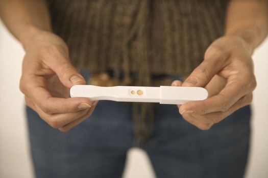 Close up of Asian woman holding pregnancy test.