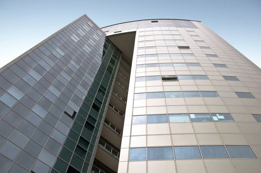 Office building with a hinged facade. Part of the facade opaque aluminum panel, part of - a complete glazing. Against the background of blue sky. Horizontal orientation.