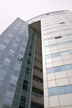 Office building with a hinged facade. Part of the facade opaque aluminum panel, part of - a complete glazing. Over white. Isolation. Vertical orientation.