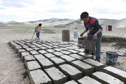 MONGOLIA, AUGUST 06, 2008 -  two  mongolian boys prepare  a brick for construction of house