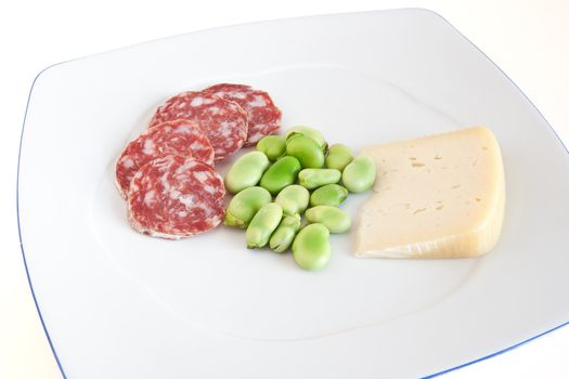 broad beans with pecorino cheese and salami slices on a white plate isolated with clipping path