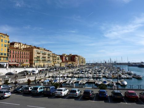 Colored buildings next to the old port with many boats and cars along at Nice, France, by beautiful weather
