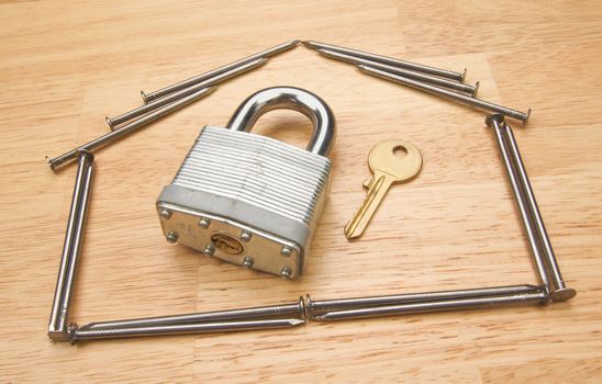 House of Nails with Lock and Key on a Wood Background.