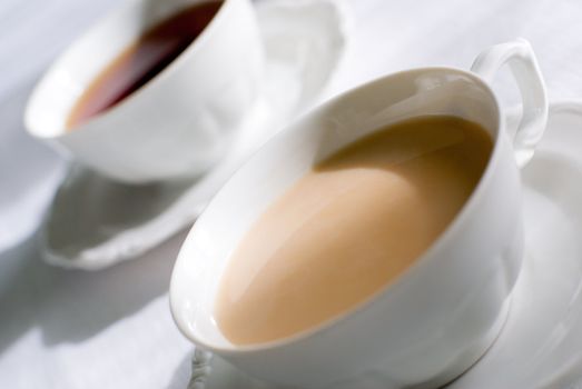 Tea or coffee set - two porcelain cup on the table, one with milk.