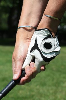 Woman holding a golfclub, wearing golf gloves