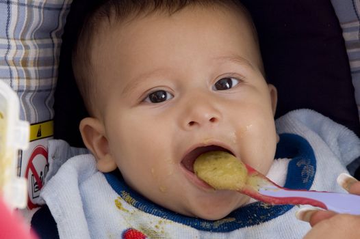 close up of cute baby eating food with spoon