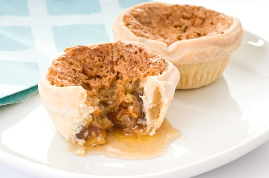 Homemade butter tarts with runny filling on plate.