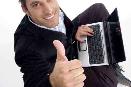 handsome accountant working on laptop gesturing thumbs up against white background