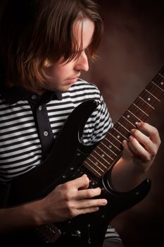 Young Musician Plays His Electric Guitar with Dramatic Lighting.