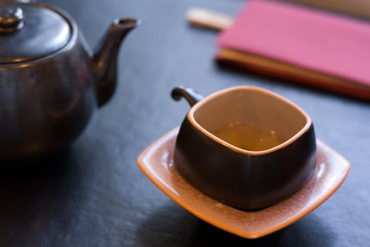 Teapot and teacup - focus on the front edge of the cup, shallow depth of field.