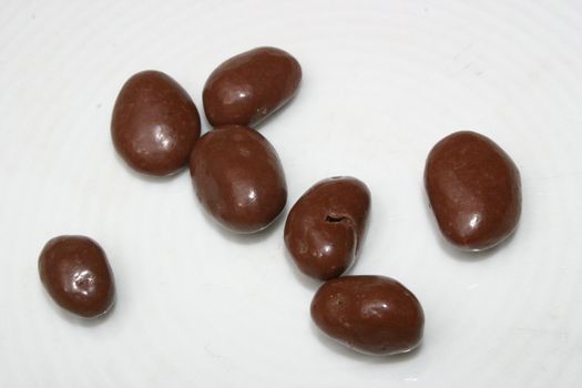 seven chocolate raisins on a white dish