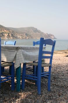 blue chairs by the sea at traditional greek taverna patmos island dodecanese greece