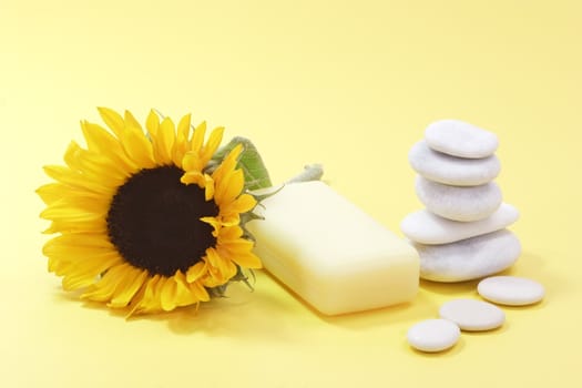 Bar of soap and a sunflower on yellow background