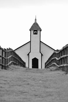 Pathway leading the viewers eye to the front of the church on a cloudy day.  Picture is in black and white to emphasize the simplicity and sanctuary of the church which is black and white itself. Alberta, Canada