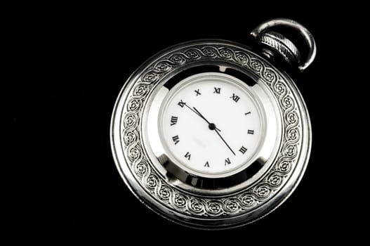 Elegant carved steel pocket watch, isolated on black