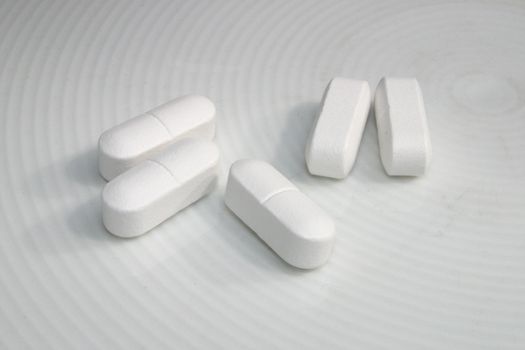 five white tablets on a white dish
