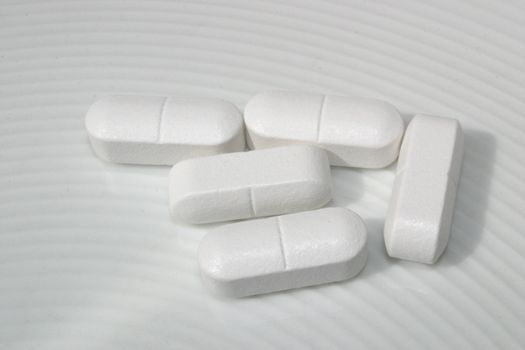 five pills on a white dish