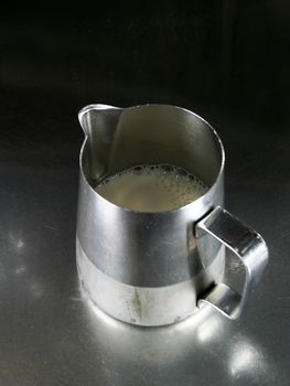 Professional milk steaming pitcher ready to to be steamed. The milk is still cold at this stage.