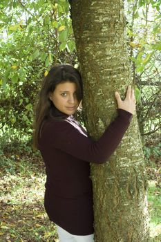 a pretty young woman hugging a tree