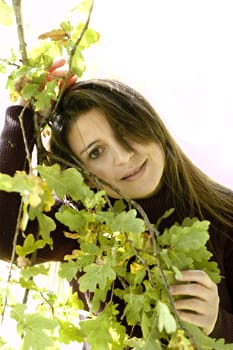 Woman lovingly holding leaves on a tree.