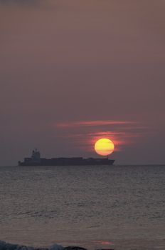 A cargo ship on the ocean in the early morning sunrise.