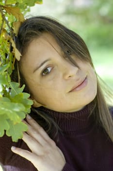 Pretty young woman against green leaves