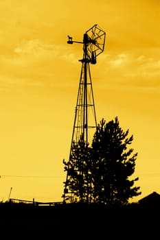 An old windmill on the prairie with yellow sky